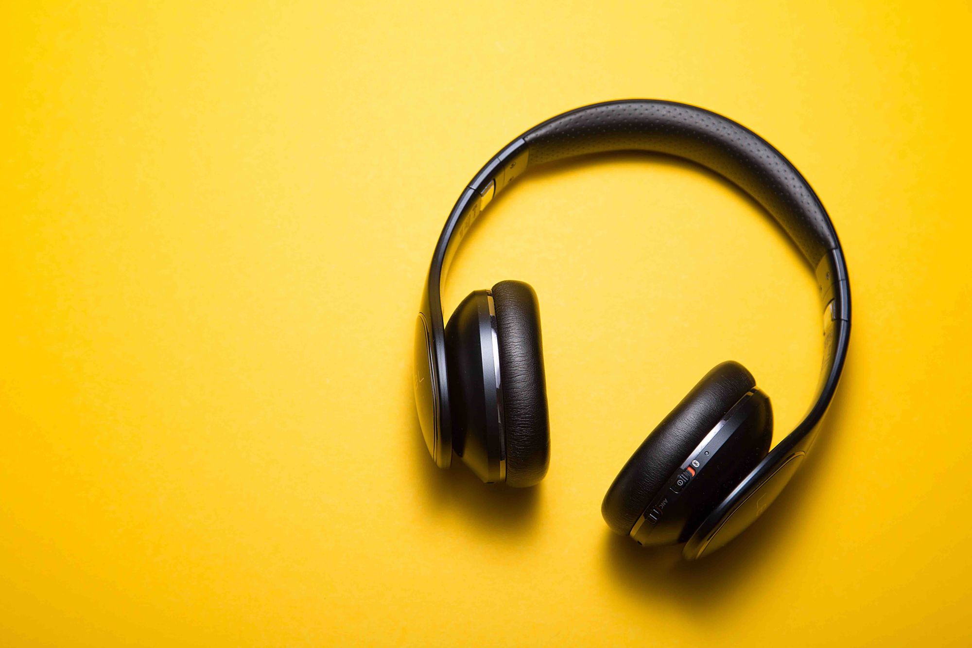 A pair of headphones on a yellow surface.