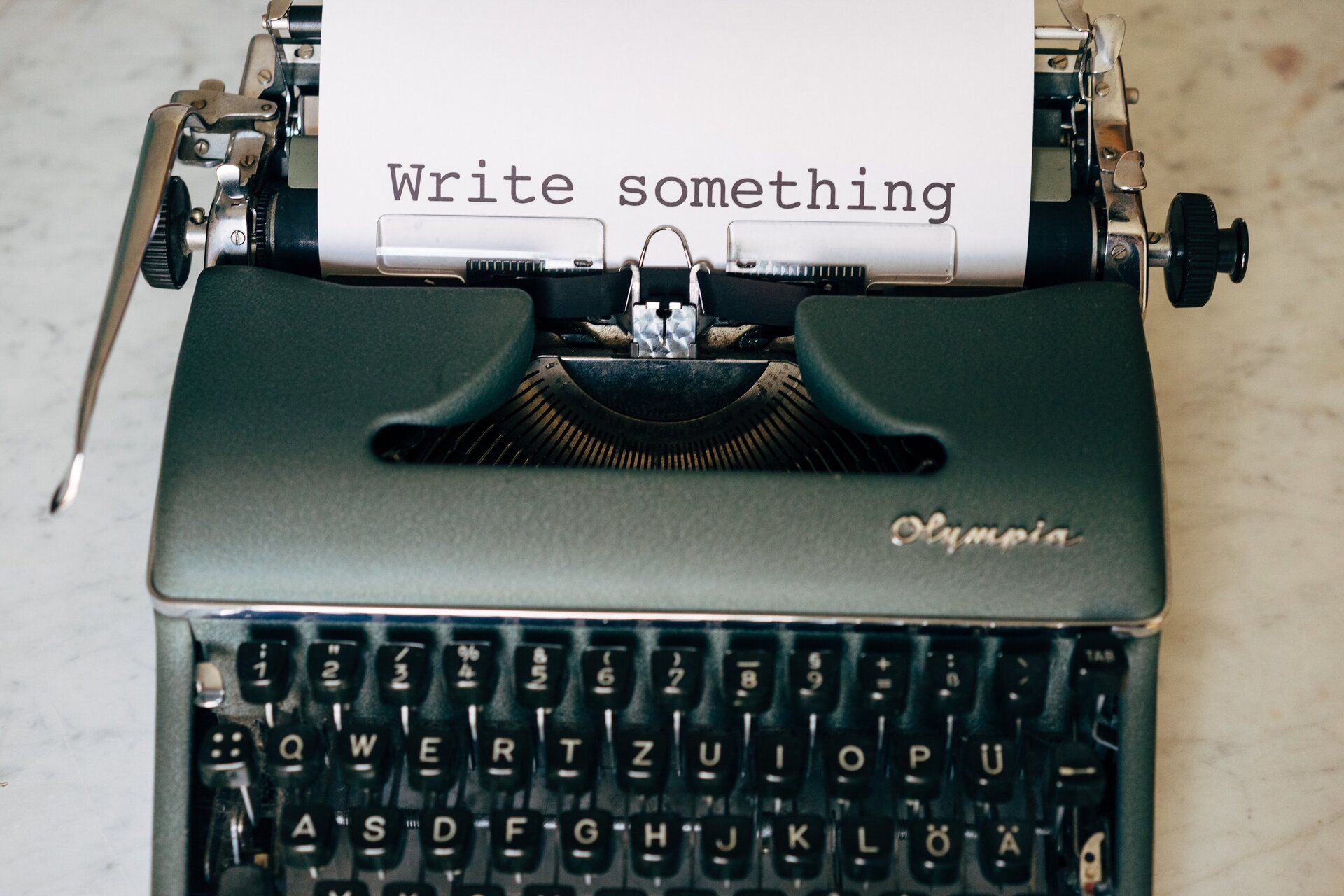 A green typewriter writing the words, "Write something".