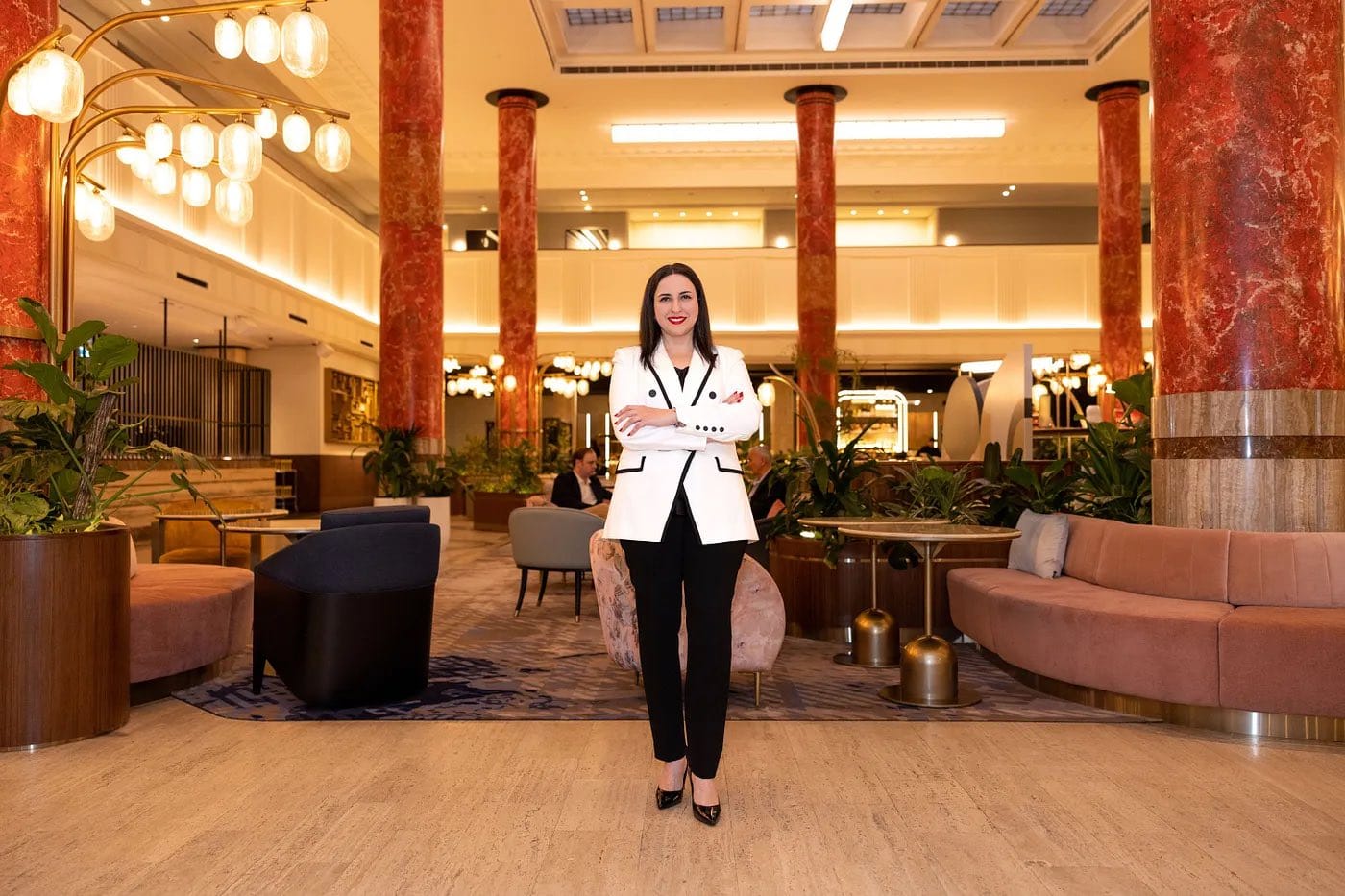 A photo of Elinor Moshe, in a suit, looking at the camera.