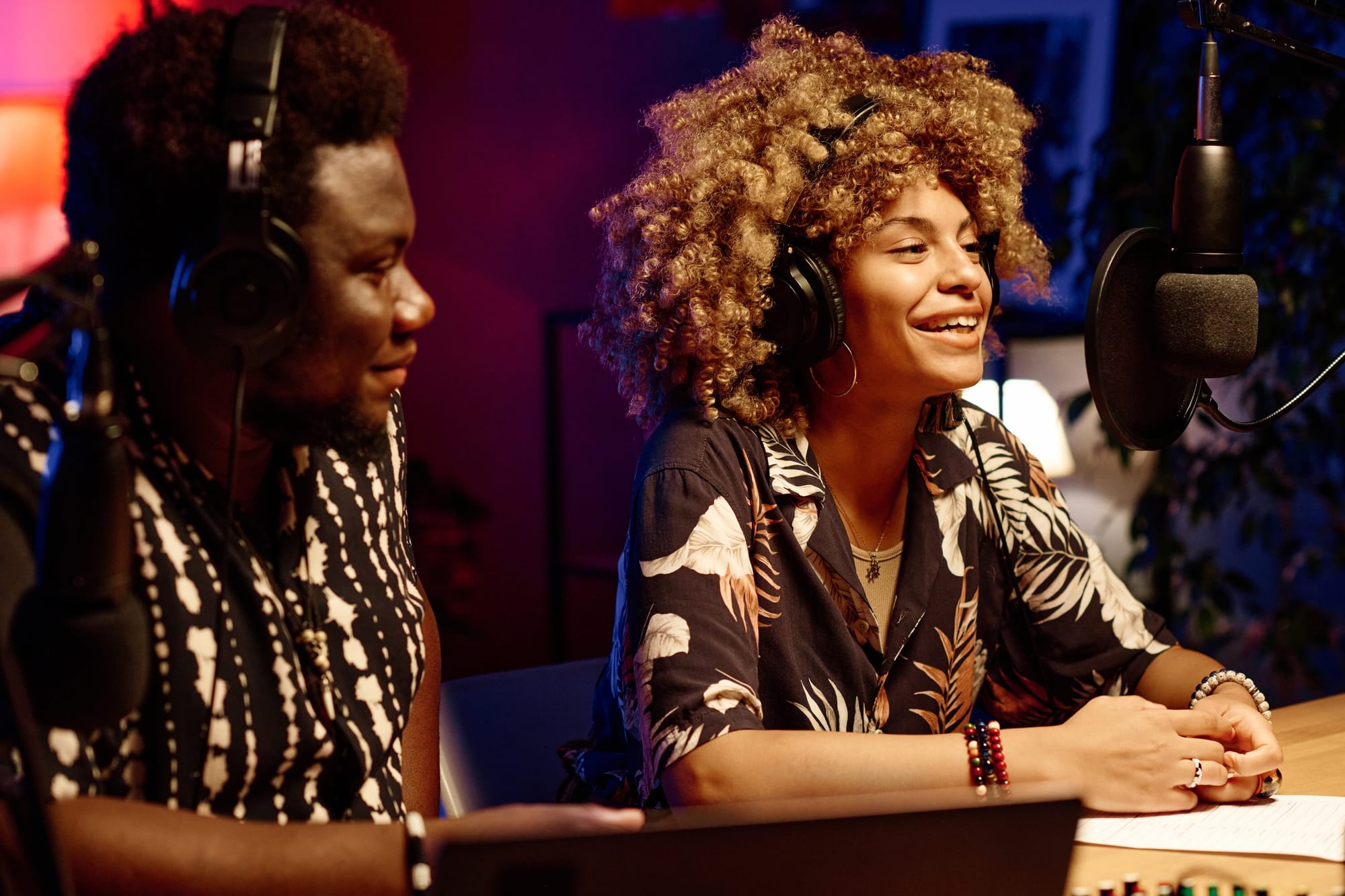 Miling Woman Sitting Next To Invited Guest And Talking Into Microphone